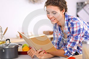 Young woman reading cookbook in the kitchen