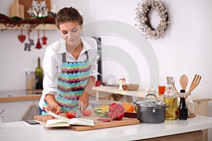 Young woman reading cookbook in the kitchen, photo