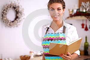 Young woman reading cookbook in the kitchen