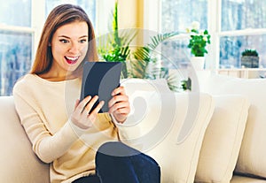 Young woman reading with an e-reader in a large room