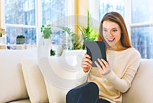 Young woman reading with an e-reader in a large room