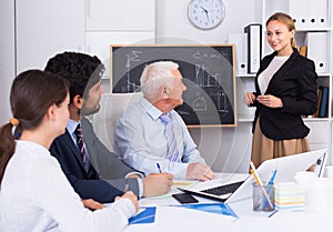 Young woman is reading financial report to colleagues on meeting