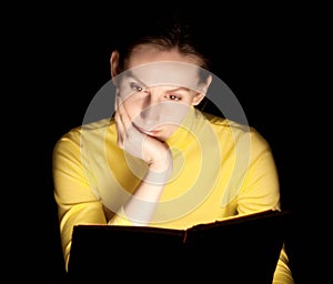 Young woman reading glowing book