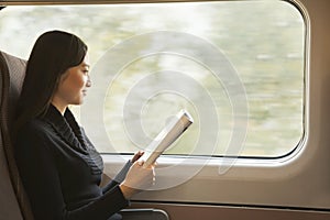 Young Woman Reading a Magazine While Riding the Train