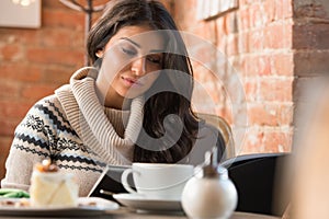 Young woman reading menu in a cafe indoors