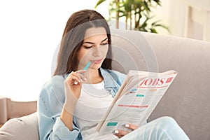 Young woman reading newspaper indoors