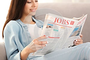 Young woman reading newspaper indoors