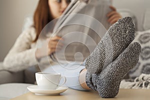 Young woman reading newspaper sitting sofa