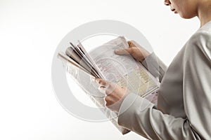 Young woman reading newspaper on white background