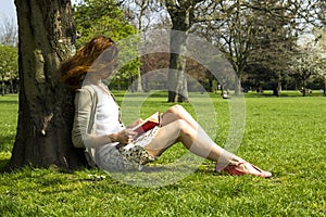 Young woman reading under a tree