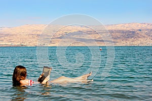 Young woman reads a book floating in the Dead Sea in Israel