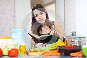 Young woman reads cookbook for recipe