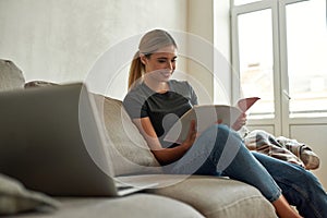 Young woman reads documents while sitting on couch