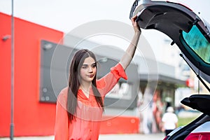 Young woman realizing she forgot something looking in the empty trunk of the car. Woman holding car trunk open