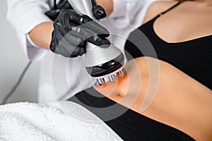 Young woman receives RF body cavitation lifting treatment at a beauty salon to target fat reduction