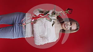 Young woman receives rose and becomes happy on red background
