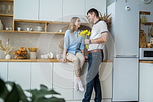 A young woman receives yellow daffodils as a gift from her husband or partner, smiling at him