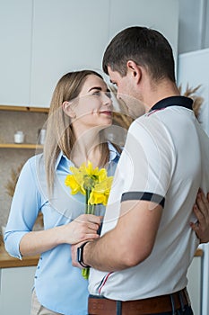 A young woman receives yellow daffodils as a gift from her husband or partner, smiling at him