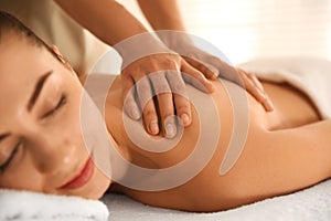 Young woman receiving back massage in spa salon