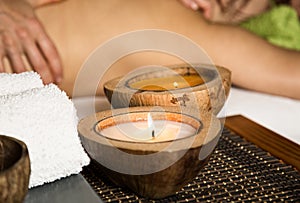 Young woman receiving a back massage in the spa salon. close-up of a candle and towels