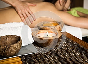 Young woman receiving a back massage in the spa salon. close-up of a candle and towels