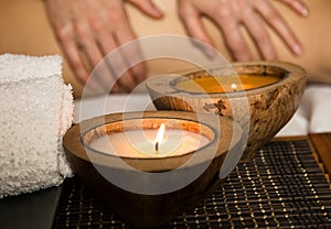 Young woman receiving a back massage in the spa salon. close-up of a candle and towels