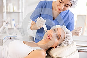 Young woman receiving cosmetic facial radiofrequency facial procedure