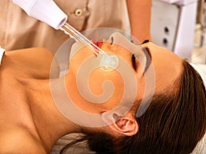 Young woman receiving electric facial massage.