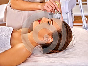 Young woman receiving electric facial massage. photo