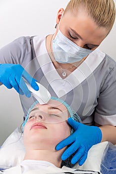 Young woman receiving electric galvanic anti-aging face spa massage at beauty salon