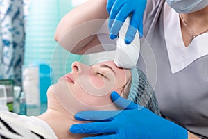 Young woman receiving electric galvanic anti-aging face spa massage at beauty salon