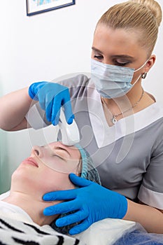 Young woman receiving electric galvanic anti-aging face spa massage at beauty salon