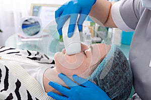 Young woman receiving electric galvanic anti-aging face spa massage at beauty salon