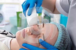 Young woman receiving electric galvanic anti-aging face spa massage at beauty salon