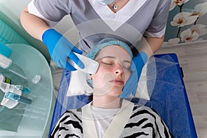 Young woman receiving electric galvanic anti-aging face spa massage at beauty salon