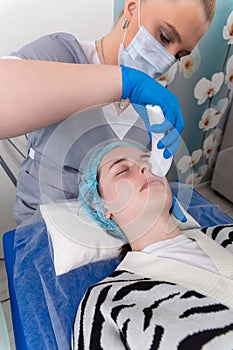 Young woman receiving electric galvanic anti-aging face spa massage at beauty salon