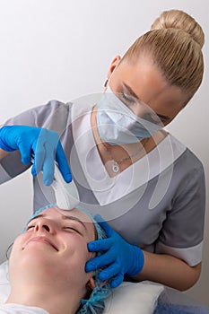 Young woman receiving electric galvanic anti-aging face spa massage at beauty salon