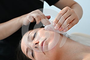 Young woman receiving facial massage with gua sha tool in beauty salon. Close up. Beauty salon