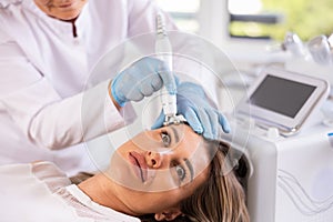 Young woman receiving facial radiofrequency procedure to tighten skin