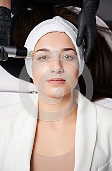 Young woman receiving facial treatment in cosmetology clinic.