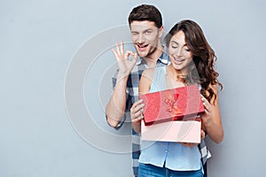 Young woman receiving gift from her boyfriend over gray background