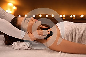 Young woman receiving hot stone massage at modern spa