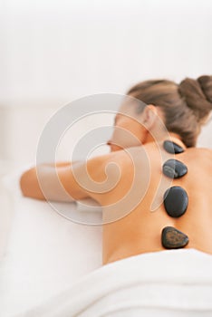 Young woman receiving hot stone massage. rear view