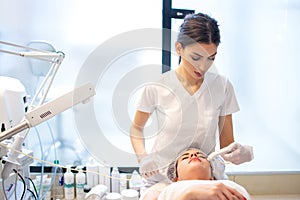 Young woman receiving hydrafacial therapy at beauty salon.