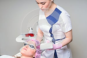 Young woman receiving laser treatment in cosmetology clinic. Eyes covered with protection glasses