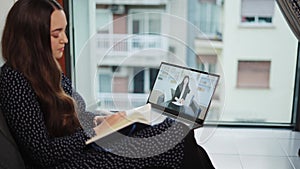 Young woman receiving online psychoterapy consultation while sitting on sofa with laptop at home