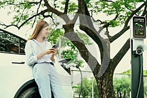 Young woman recharge EV electric vehicle battery from EV charging station. Exalt