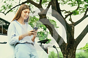 Young woman recharge EV electric vehicle battery from EV charging station. Exalt