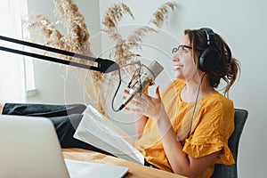 Young woman recording podcast on his laptop computer with headphones and microphone