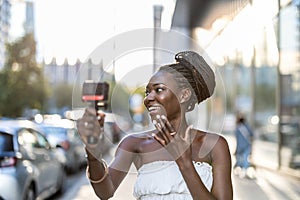 Young woman recording a video with a camera in a city